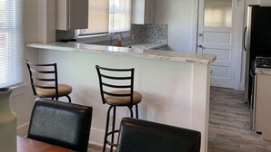 A compact kitchen with a central island, a dining area with two chairs, and a refrigerator. - 🏡⭐️Charming 2 bed. historical house -Centrl El Paso
 (El Paso)