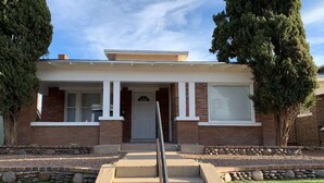 A two-story house with a front porch, a brick facade, and a stone pathway leading to the front door. - 🏡⭐️Charming 2 bed. historical house -Centrl El Paso
 (El Paso)