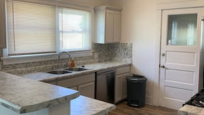 A compact kitchen with white cabinets, a marble countertop, a sink, and a dishwasher. - 🏡⭐️Charming 2 bed. historical house -Centrl El Paso
 (El Paso)