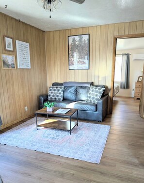 A cozy living room with a leather sofa, a coffee table, and a rug. - Willows Cabin at Lazy Oaks Resort (Lakeside)