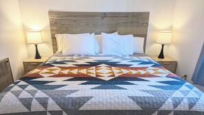 A bed with a geometric patterned quilt, two bedside lamps, and a wooden headboard. - Willows Cabin at Lazy Oaks Resort (Lakeside)