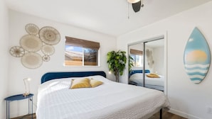 A bedroom with a large bed, a mirror, a surfboard decoration, and a window with a view of the outside. - Maldives Vibe | Ping-Pong | Firepit I Yoga (Austin)
