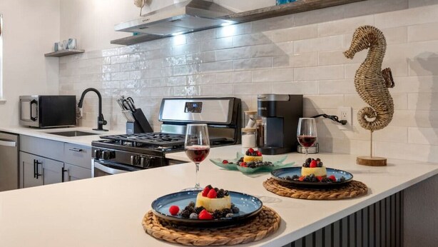 A modern kitchen with a central island, stainless steel appliances, and decorative items. - Maldives Vibe | Ping-Pong | Firepit I Yoga (Austin)