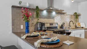 A modern kitchen with a central island, stainless steel appliances, and decorative plants. - Fun Group Travel Retreat (Austin)