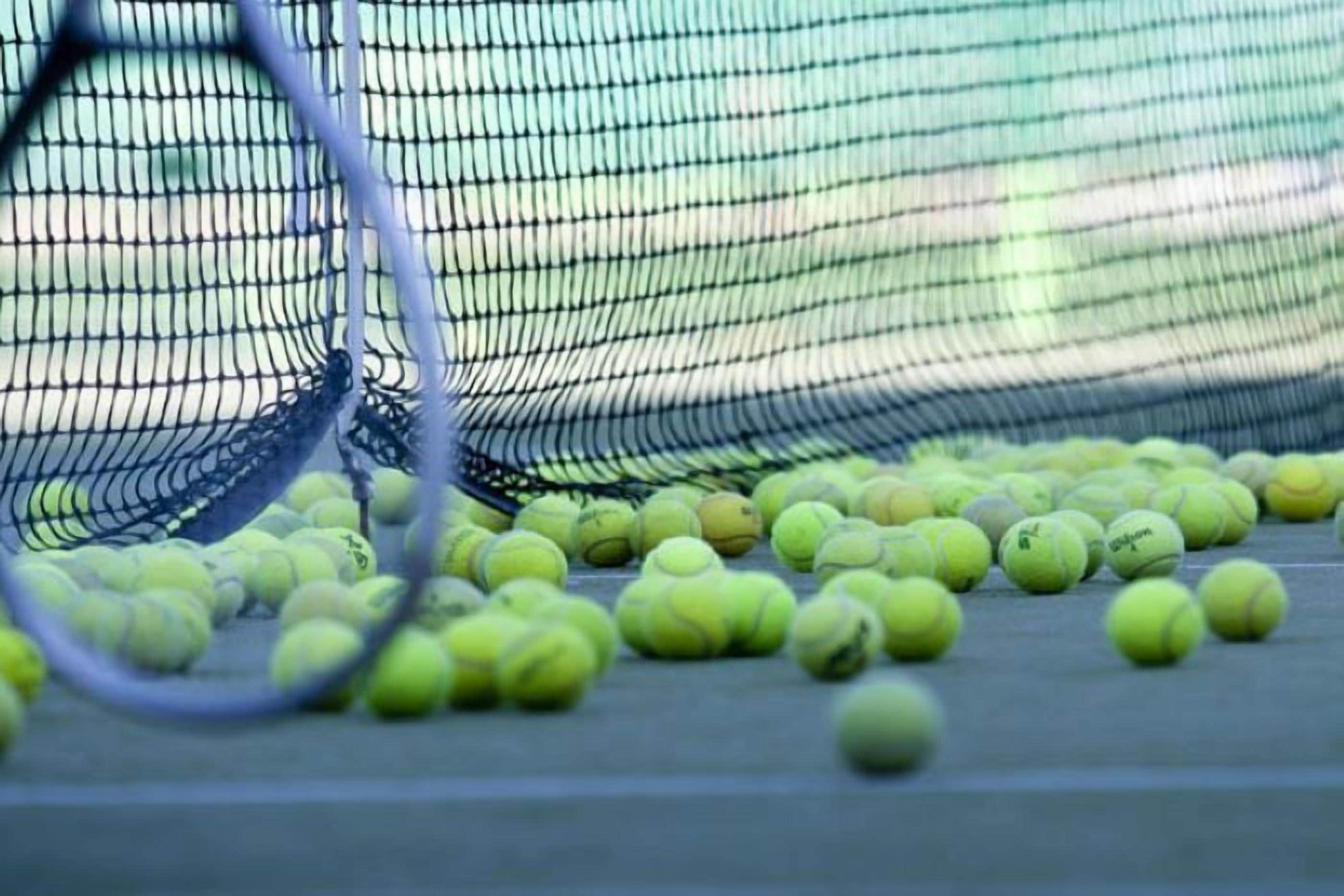 A tennis court with a net and scattered tennis balls.