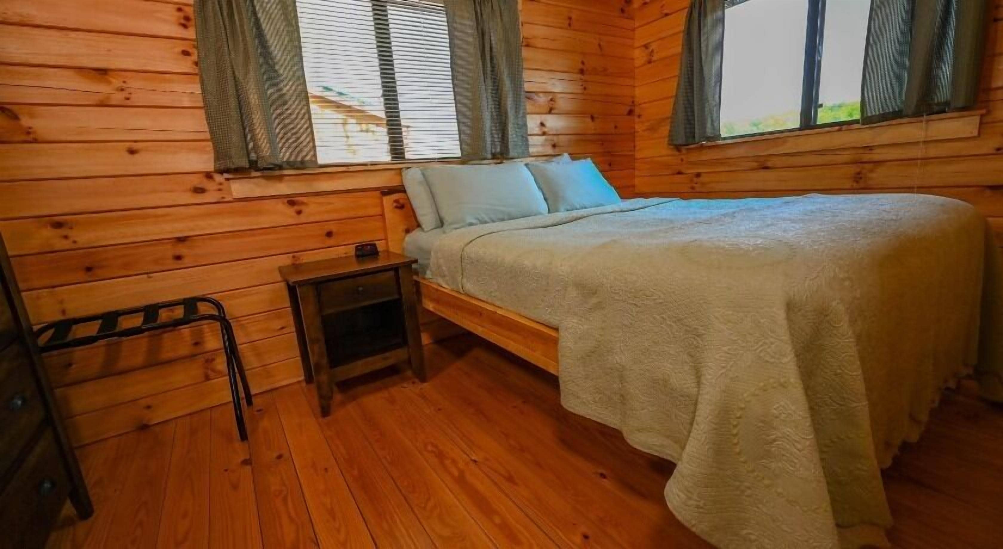 Un dormitorio de cabaña de madera con una cama, una mesita de noche y una pequeña mesa.