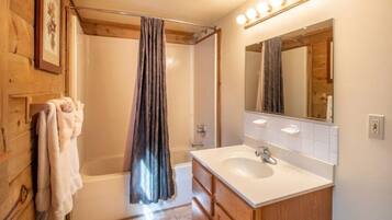 A bathroom with a bathtub, a sink, and a mirror.