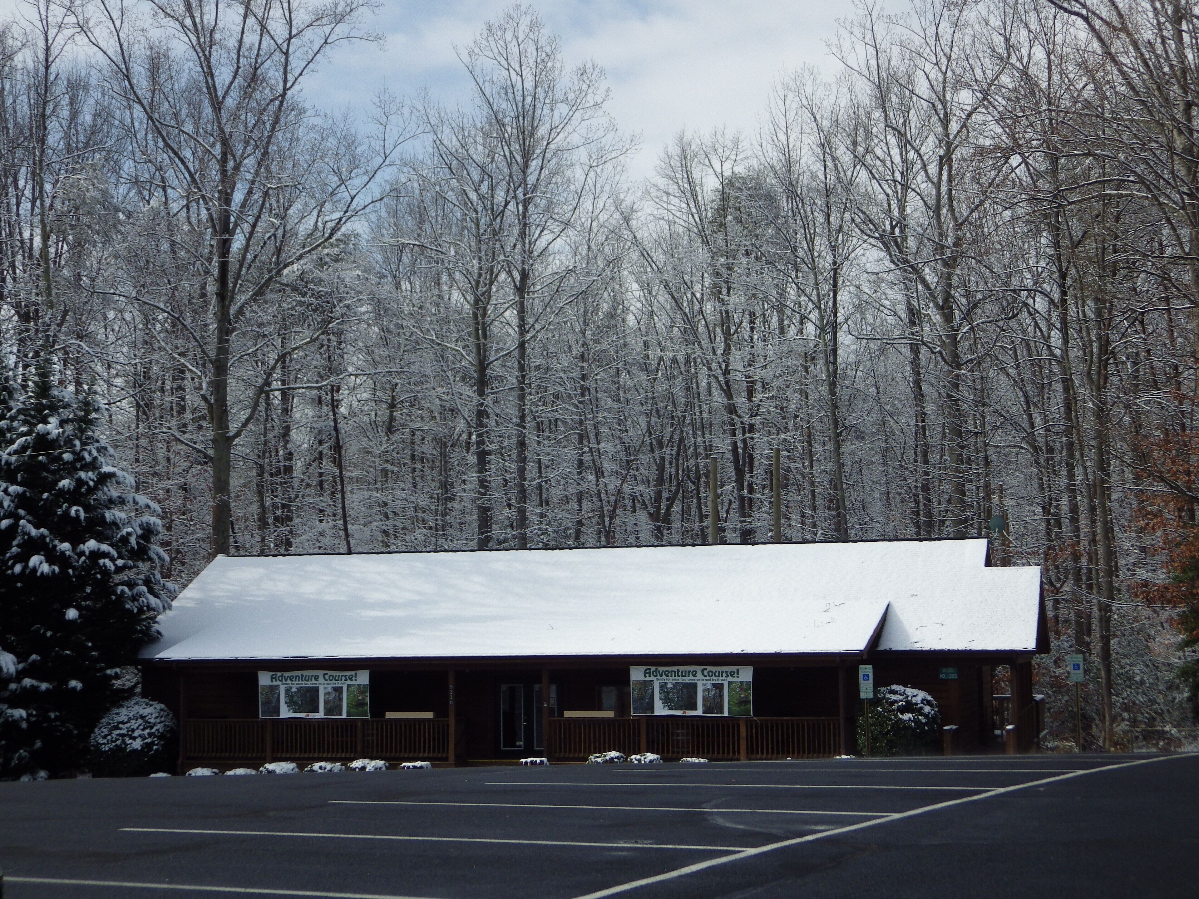Un chalet dont le toit est recouvert de neige, entouré d’une forêt.