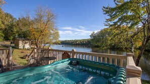 A hot tub with a wooden deck and a view of a lake. - Wilderness Presidential Resort (Spotsylvania)