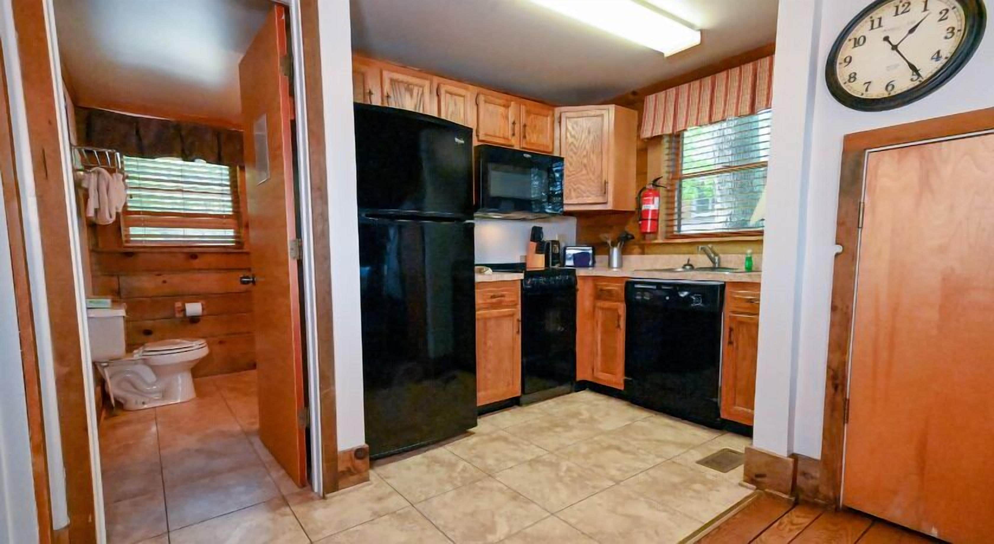 A compact kitchen with wooden cabinets, a black refrigerator, a microwave, and a dishwasher.