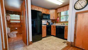 A compact kitchen with wooden cabinets, a black refrigerator, a microwave, and a dishwasher.