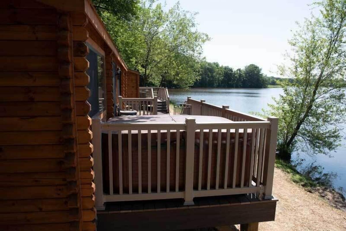 A wooden cabin with a deck overlooking a lake.