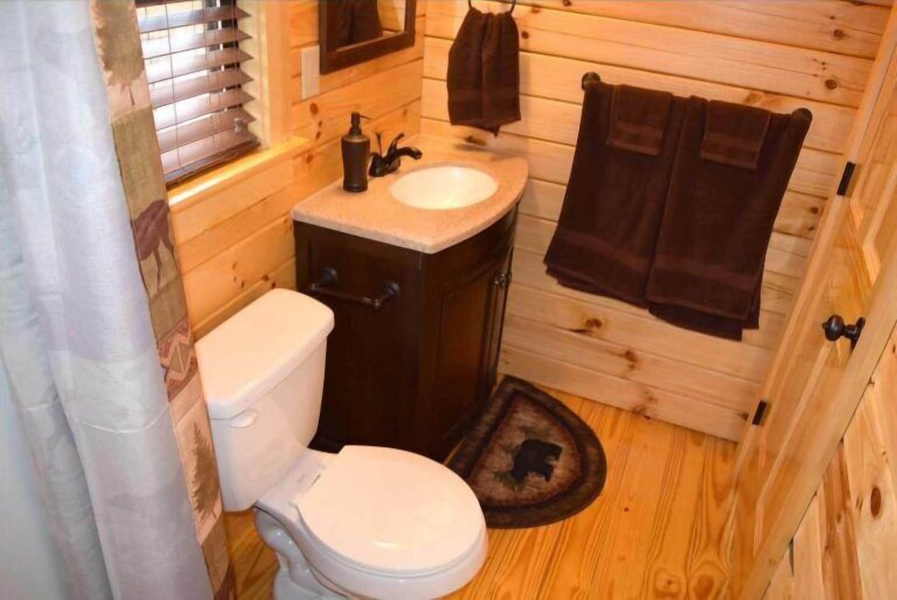 Een houten badkamer met een toilet, wastafel en handdoekhouder.