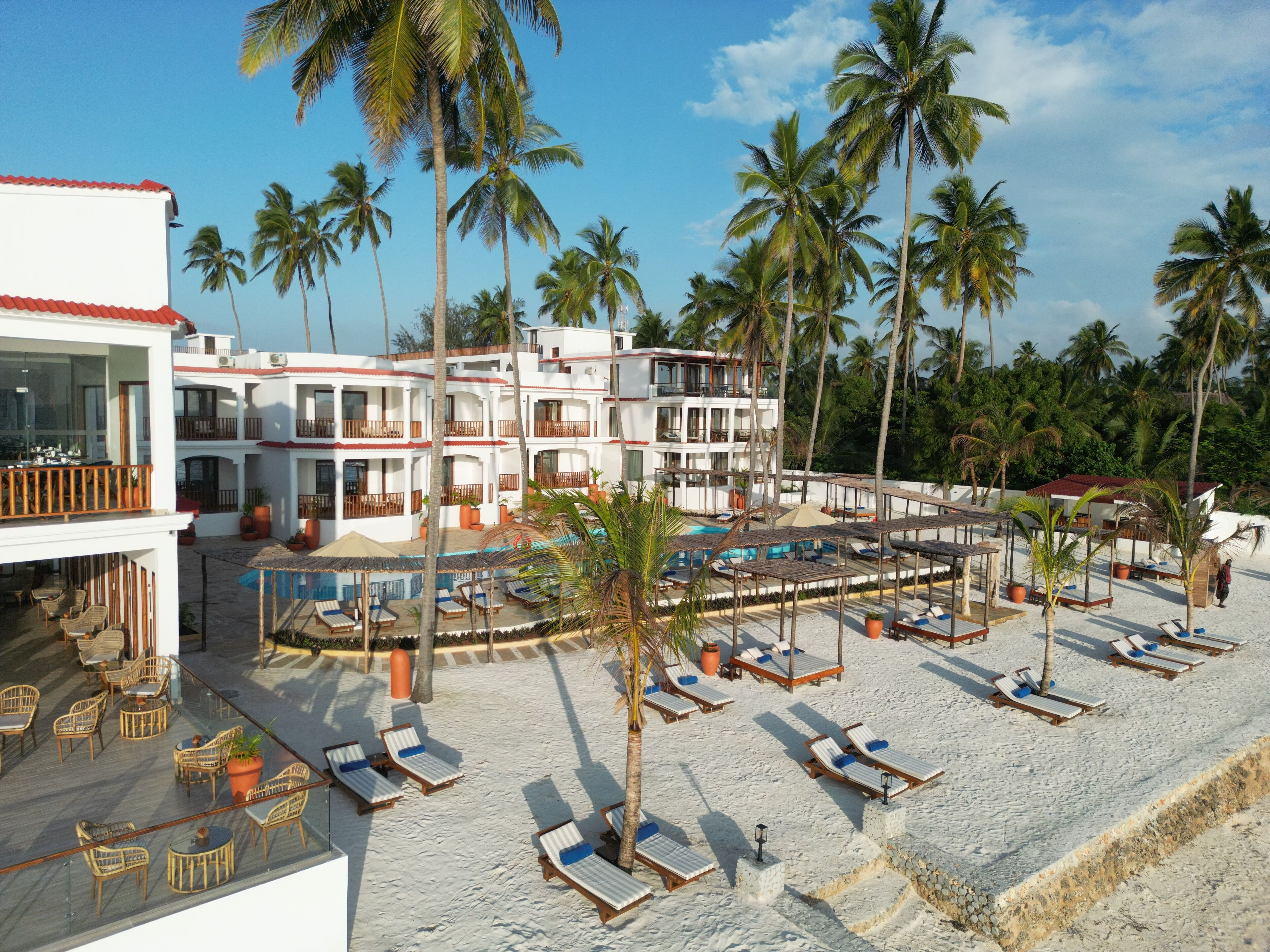 A resort with multiple swimming pools, lounge chairs, and palm trees.