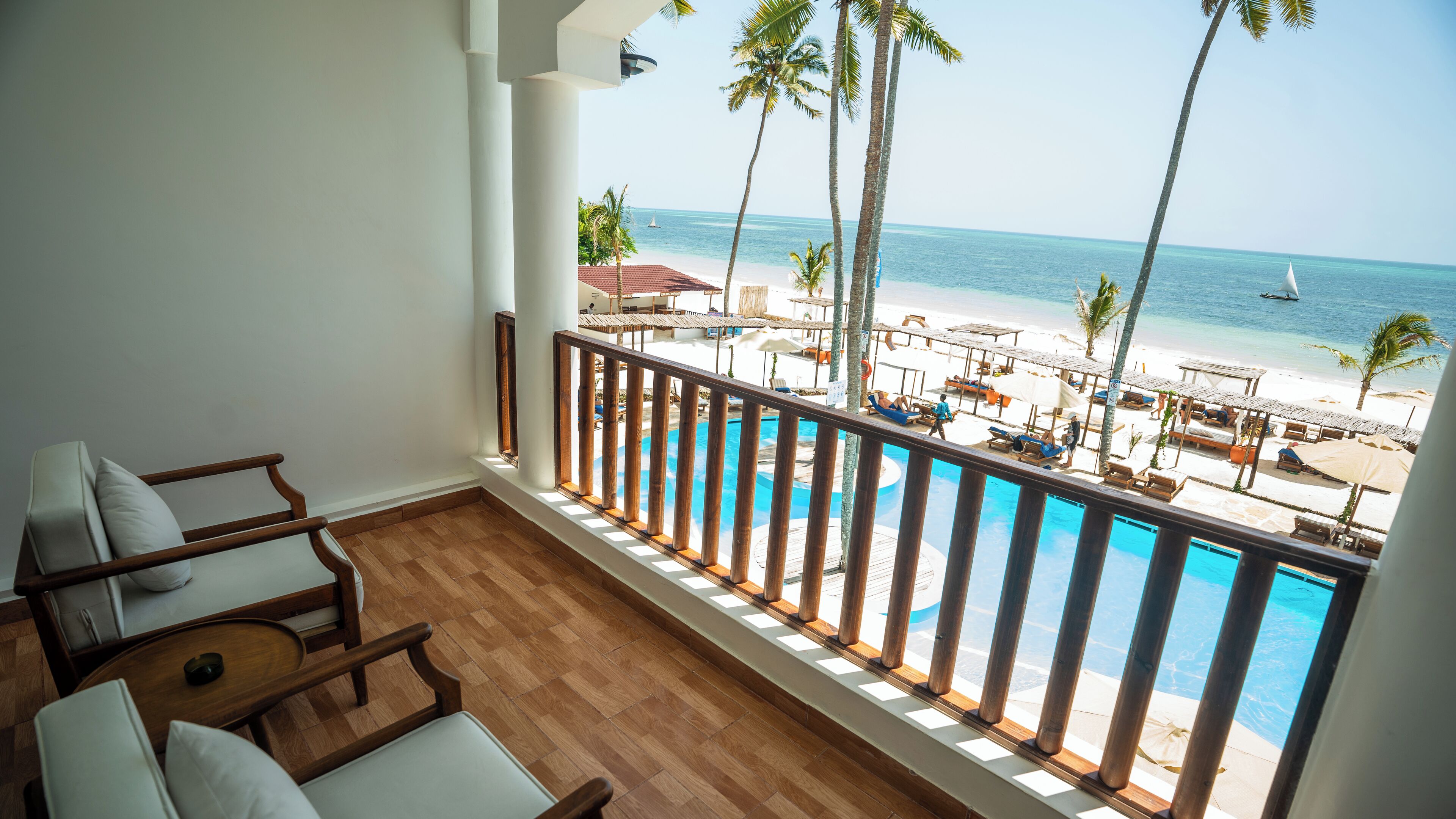 A balcony with a view of a beach and pool.