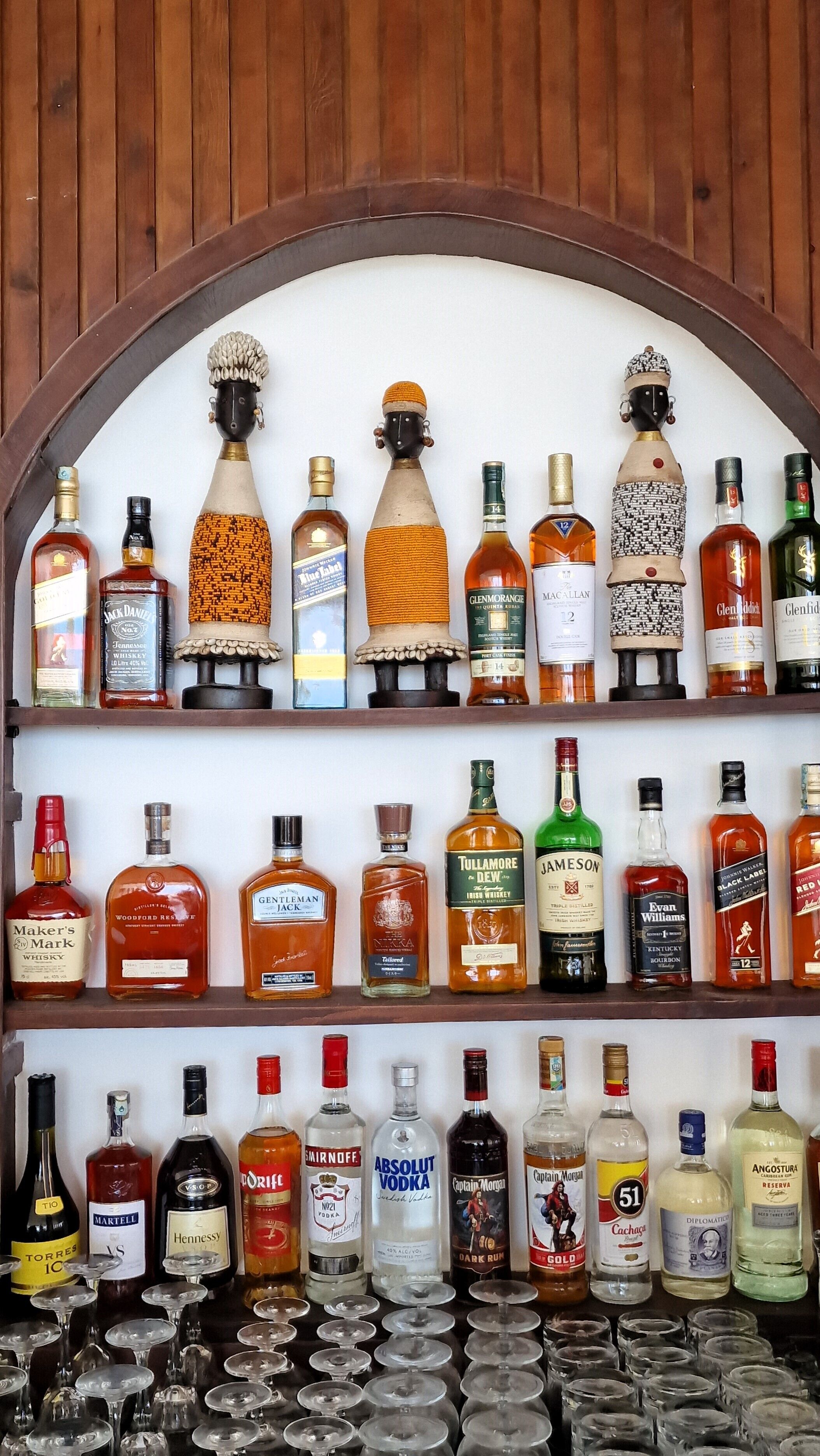 A bar with shelves of various liquor bottles and glasses.