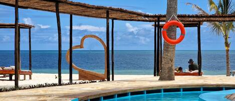 A poolside area with a wooden deck, a heart-shaped structure, and a lifebuoy.