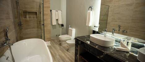 A modern bathroom with a freestanding bathtub, a toilet, and a sink with a large mirror above.