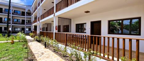 A multi-story hotel with balconies, a stone pathway, and a garden area.