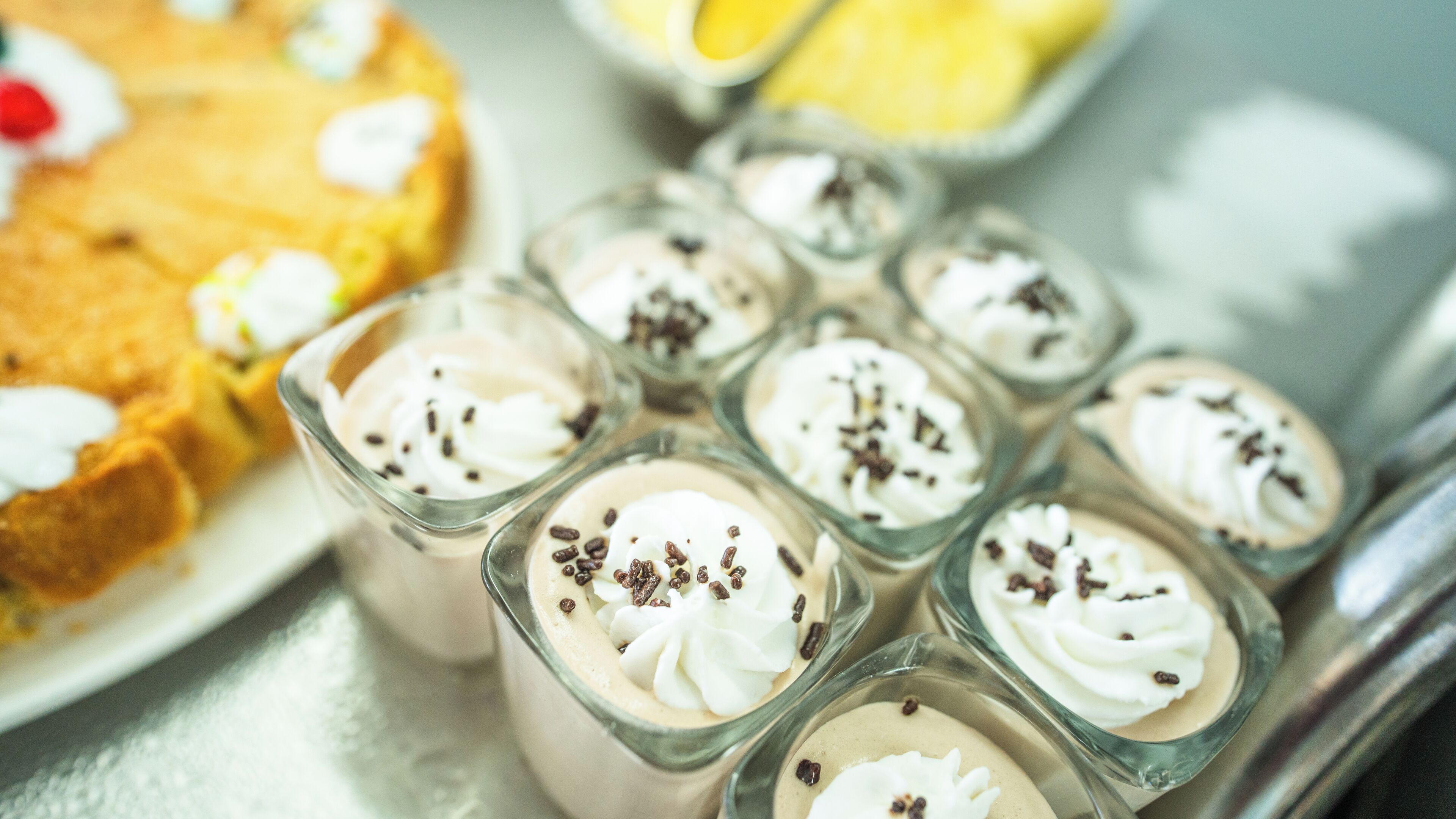 A dessert display with various creamy treats topped with whipped cream and chocolate shavings.