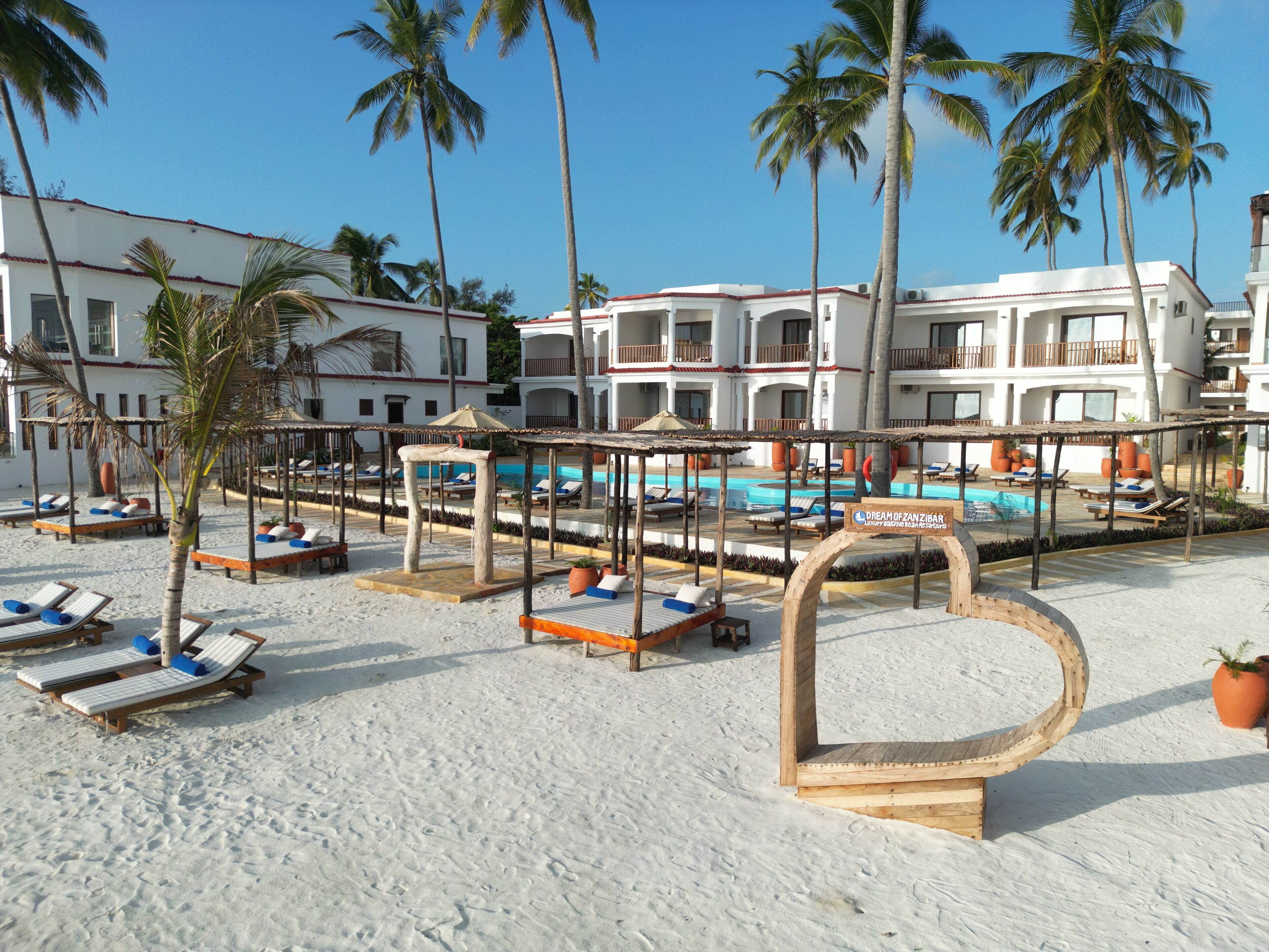 A resort with a pool area, palm trees, and beach chairs.