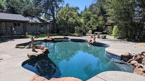 Una piscina dalla forma sinuosa, circondata da rocce e da una panca in pietra.