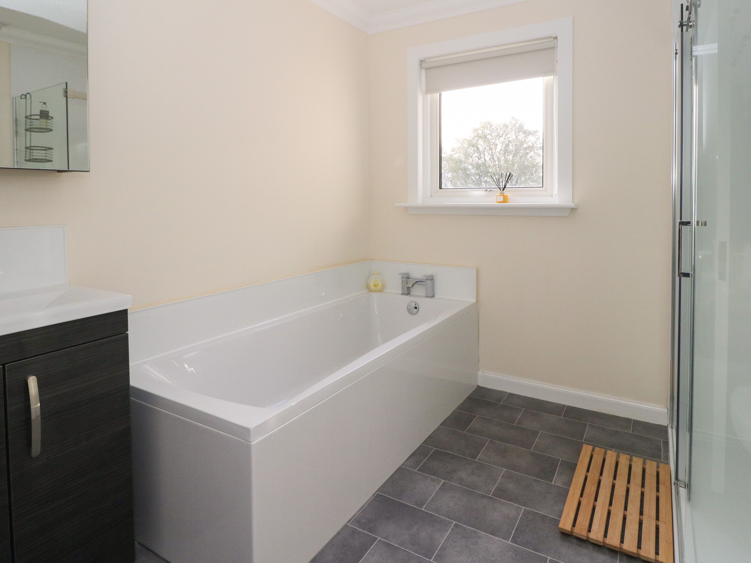 A modern bathroom with a bathtub, a window, and a shower area.