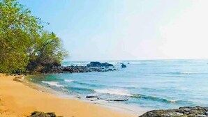 A beach with clear blue water, sandy shore, and rocky outcrops. - Almendra Beach Place (Los Cóbanos)