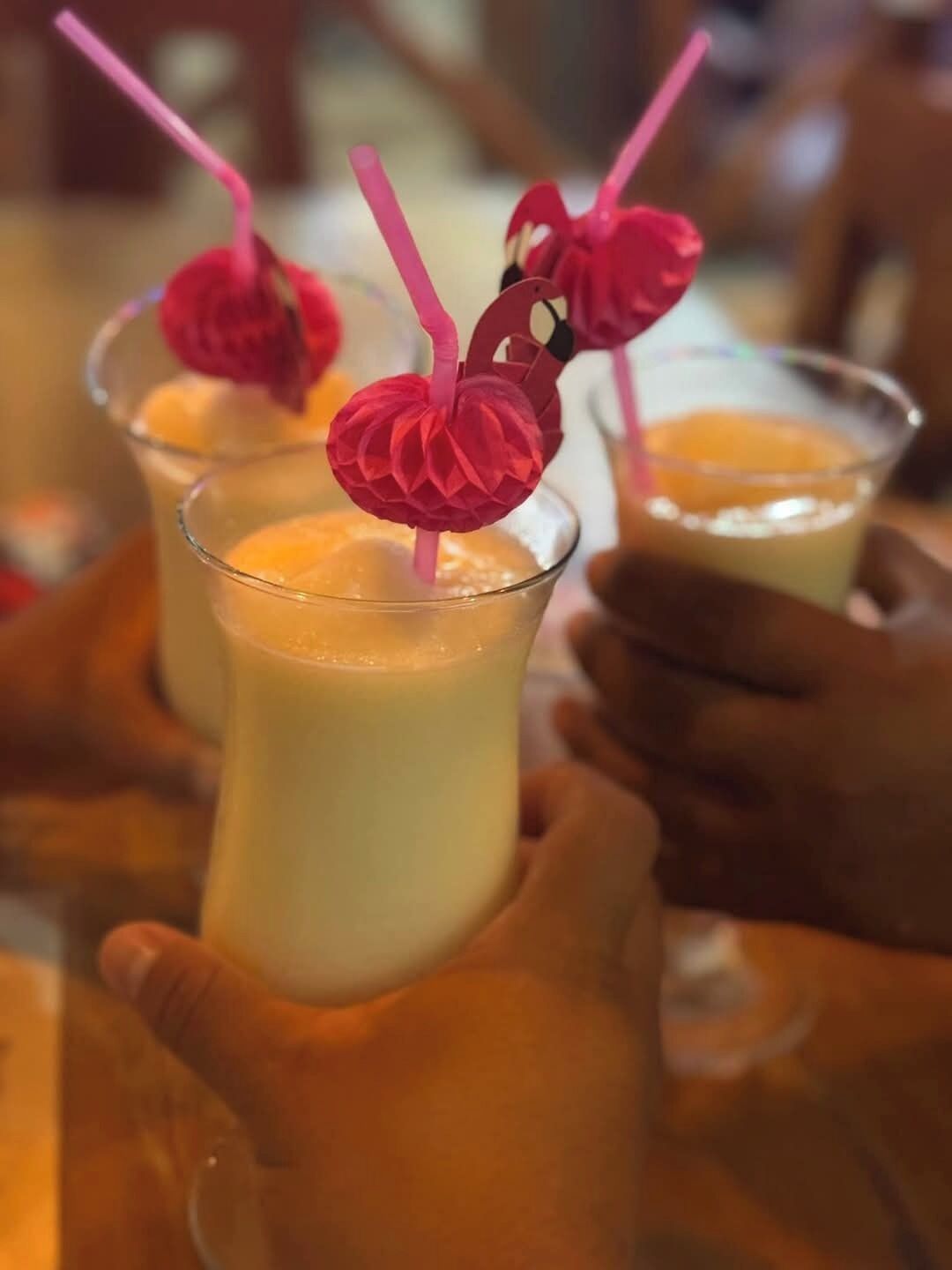 A person holding a glass with a pink straw and a decorative pink item.