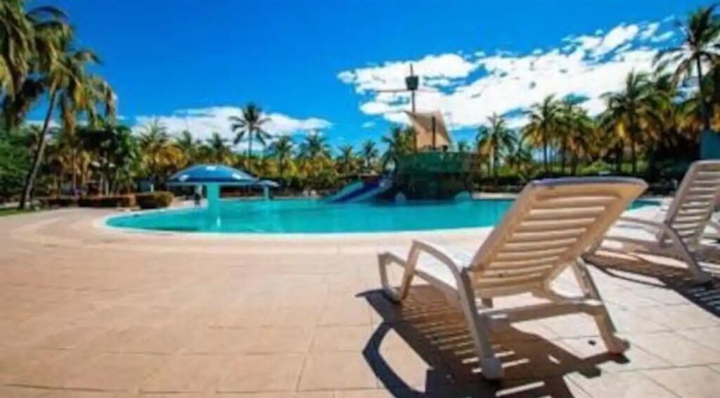 A pool area with lounge chairs and a water slide.
