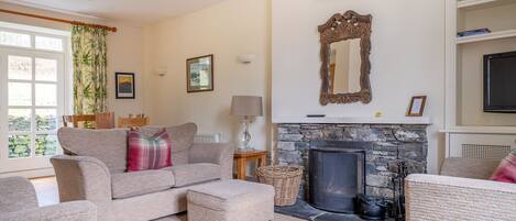 A cozy living room with a fireplace, comfortable seating, and a bookshelf.