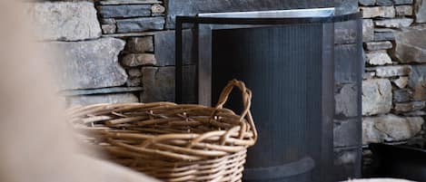 A wicker basket near a fireplace with a stone wall background.
