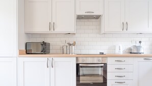 Une cuisine moderne avec des meubles blancs, un four à micro-ondes encastré, un grille-pain et un lave-vaisselle.