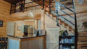 A spacious wooden interior with a central kitchen area, a staircase, and a mezzanine level. - Secluded 12-Acre Retreat w/ Hot Tub, Mountain Views, Arcade - Red River Gorge (Campton)