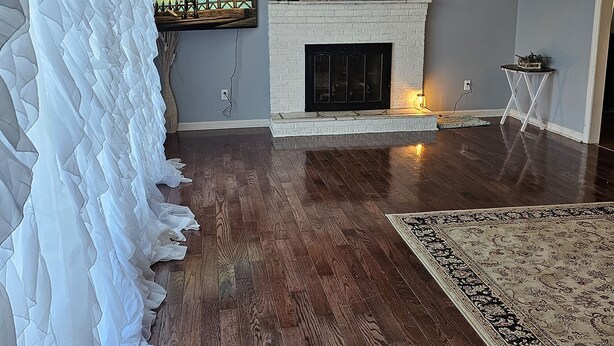 Un salon avec une cheminée, un téléviseur fixé au mur et un grand tapis.