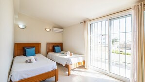 Habitación de hotel con dos camas, un ventanal grande y un equipo de aire acondicionado.