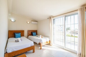 A hotel room with two beds, a large window, and an air conditioning unit. - Villa with pool and BBQ in Oura (Albufeira)