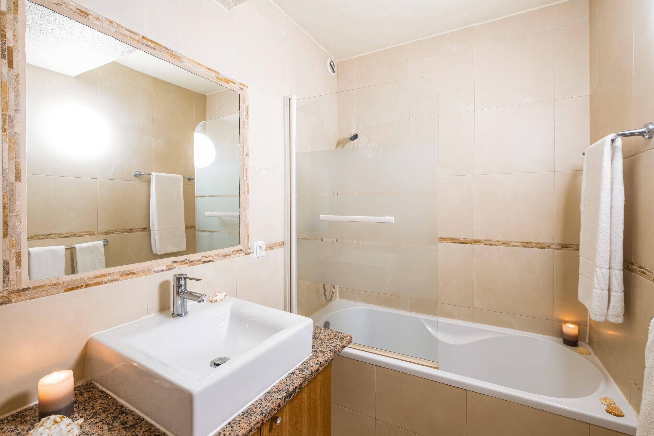 A bathroom with a sink, mirror, shower, and bathtub.