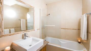A bathroom with a sink, mirror, shower, and bathtub.