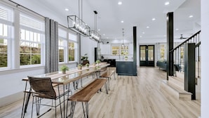 Eine geräumige Küche mit einem langen Holztisch, Bänken und moderner Pendelleuchten.