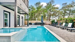 Un espace piscine aménagé avec des chaises longues et un barbecue.