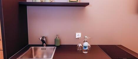 A modern kitchen with a stainless steel sink, a built-in oven, and a wooden cabinet below.