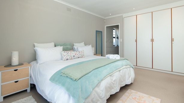 Une chambre à coucher avec un lit, une table de chevet, une armoire et une porte menant à la salle de bain.