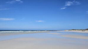 Une plage avec un large rivage sablonneux et des vagues douces.