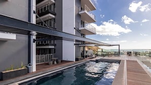 Un bâtiment moderne doté d’une piscine sur le toit, d’un espace extérieur aménagé et offrant une vue sur la ville.