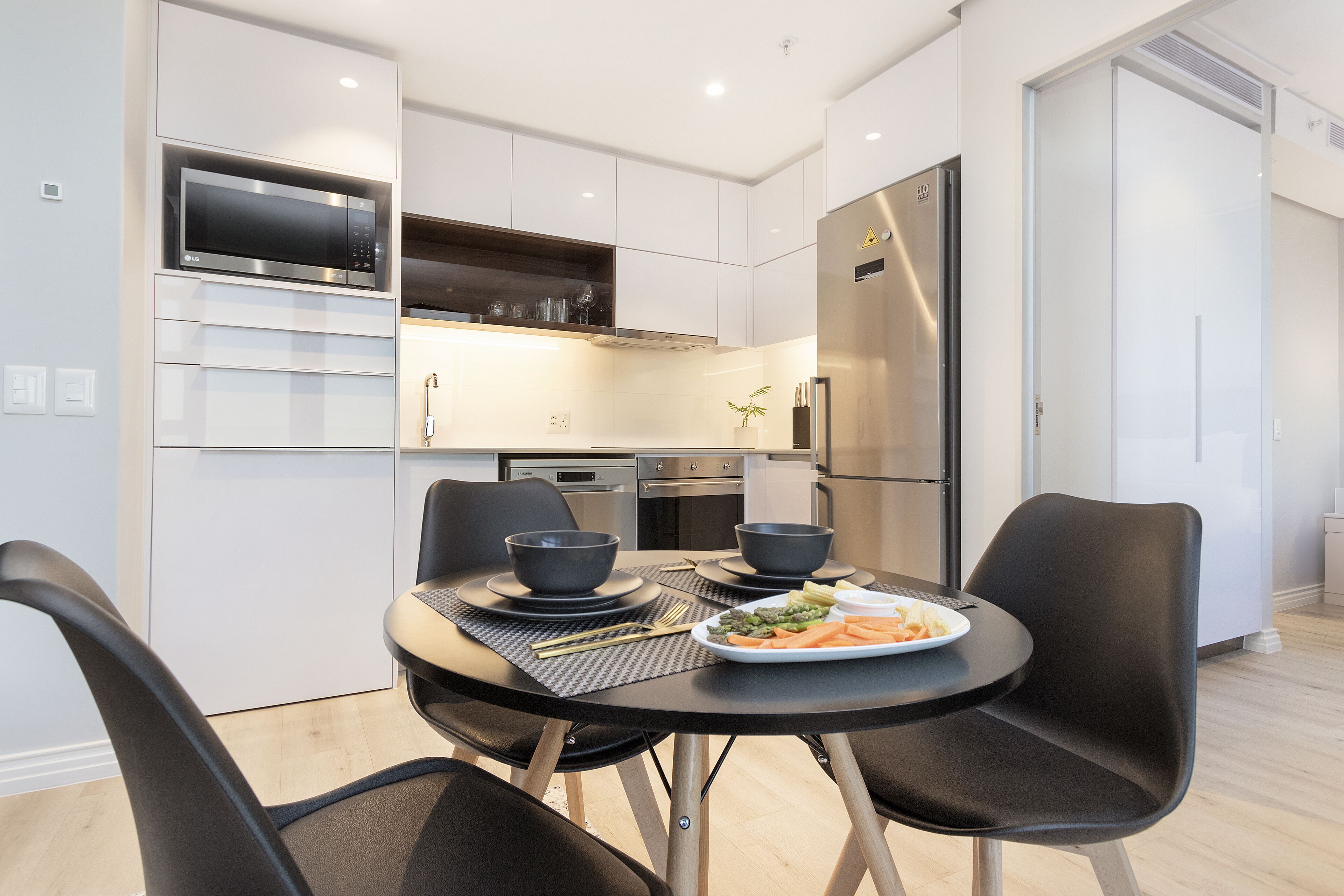Een moderne keuken met ingebouwde apparatuur, een eettafel met stoelen en een bord eten.