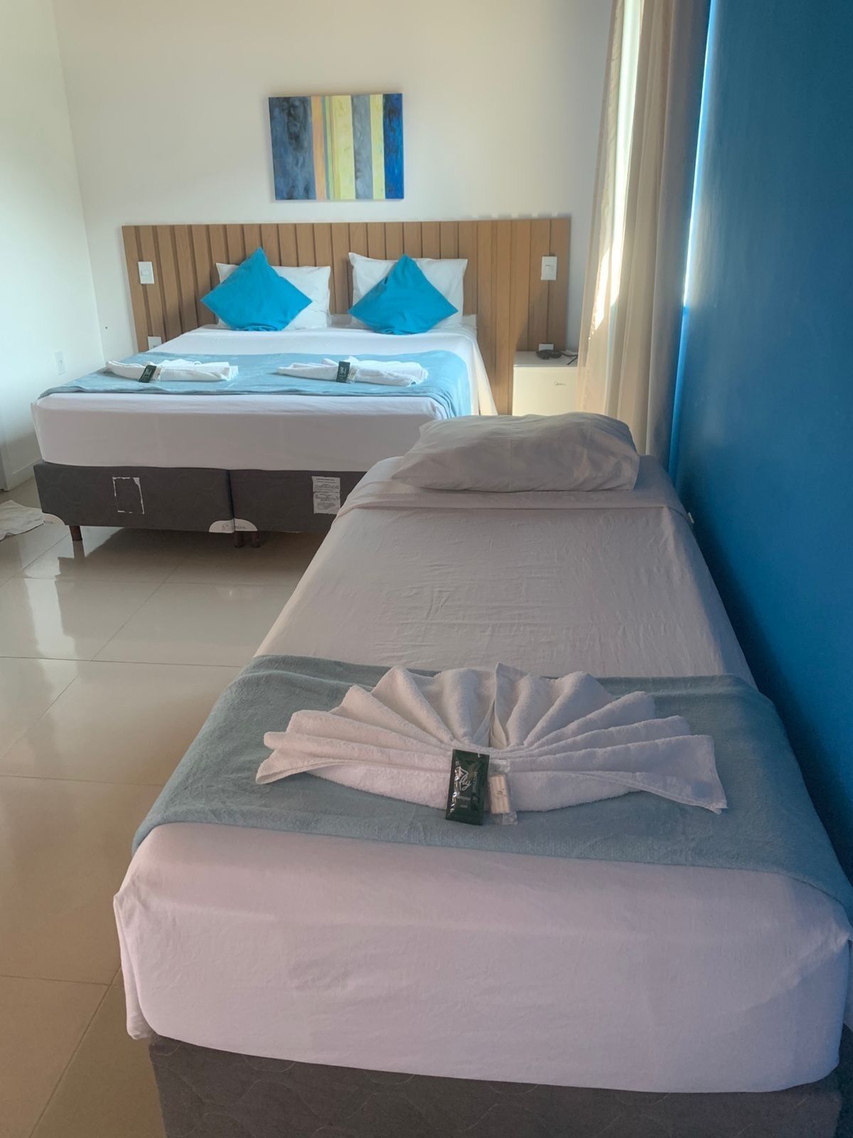 Een hotelkamer met twee bedden, één met blauw beddegoed en de ander met wit beddegoed.