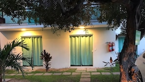 A building with a paved pathway leading to a door with a green curtain. - Foca Guest House (Búzios)
