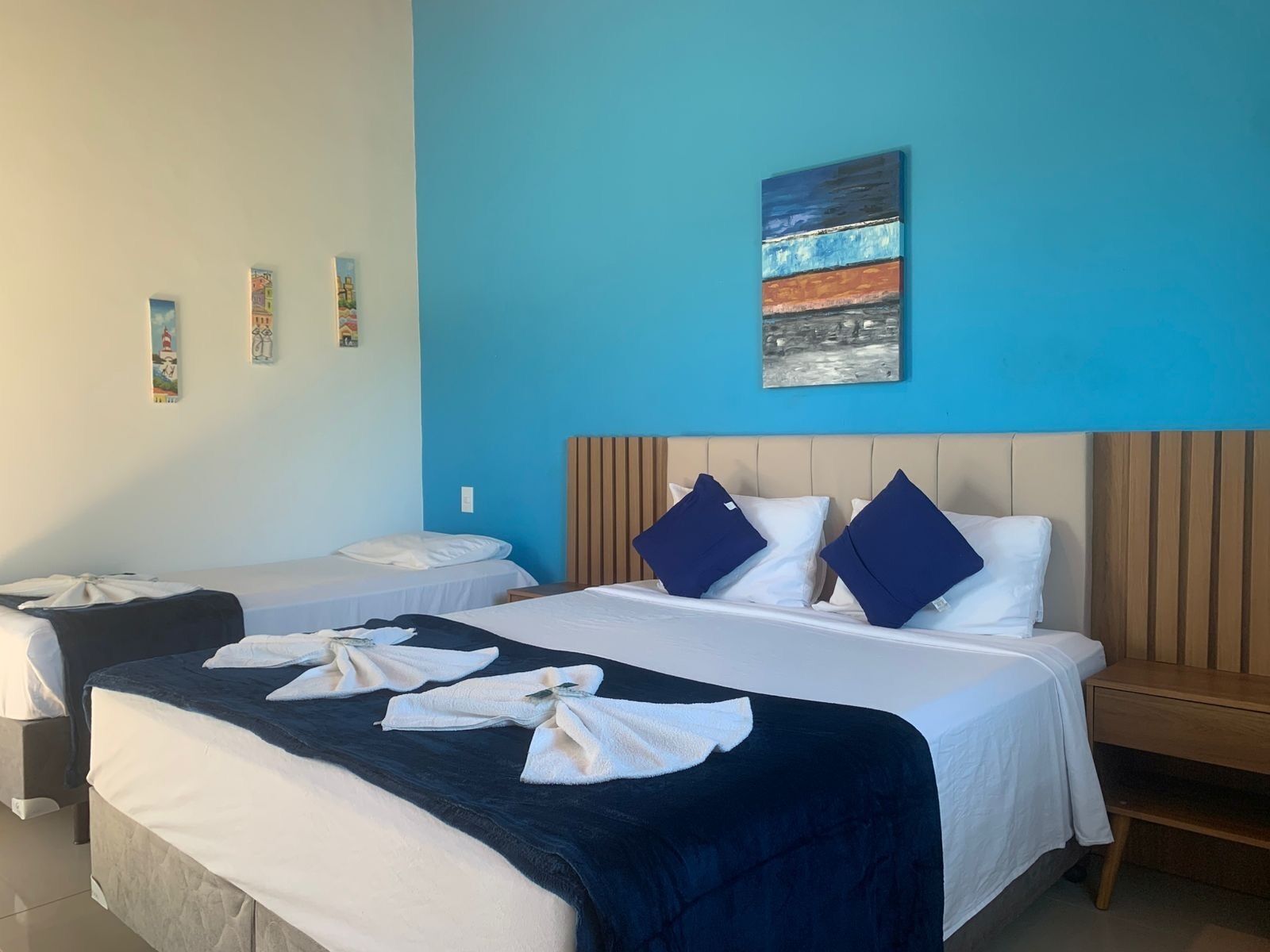 A hotel room with a large bed, two smaller beds, and a wooden headboard.