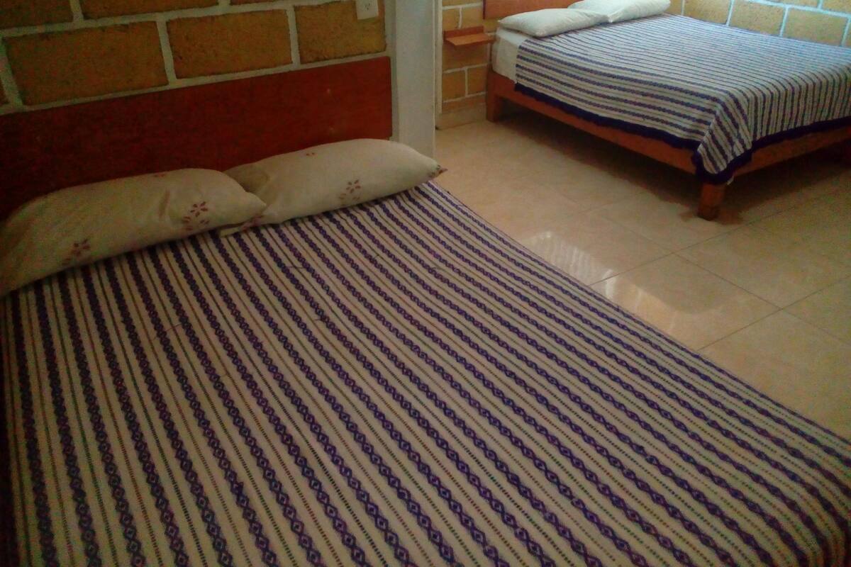 Un dormitorio con dos camas, cada una con una colcha a rayas.